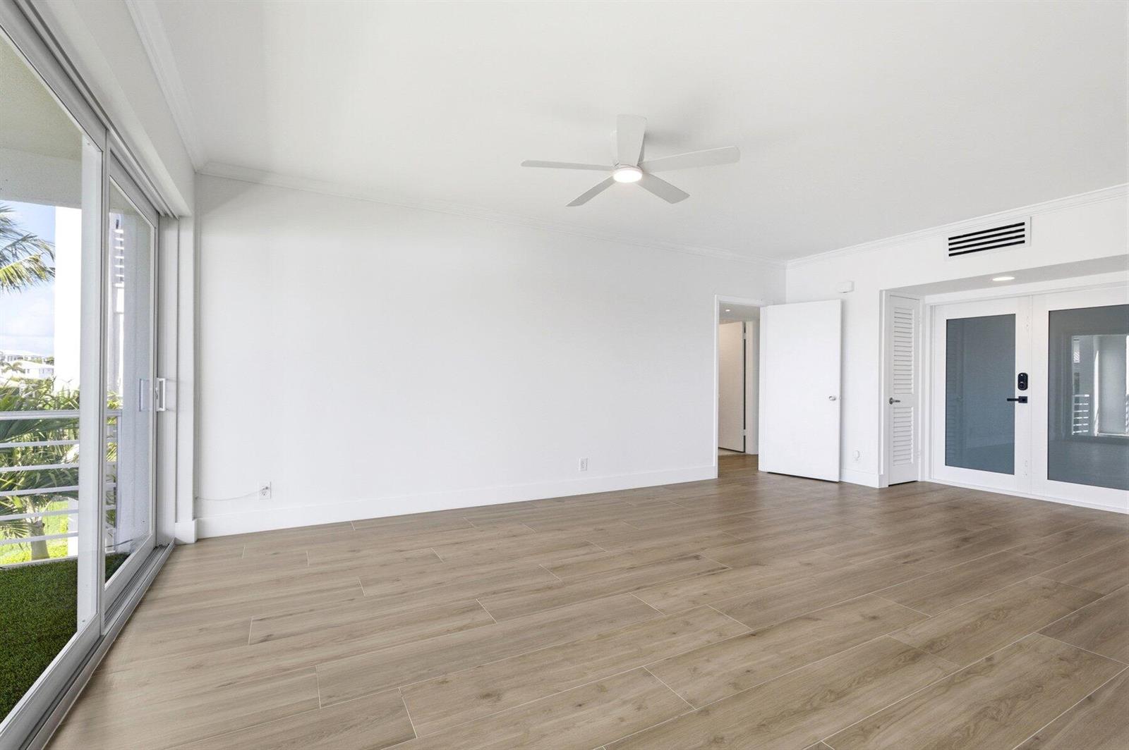 An empty room with light wood-look flooring, white walls, a ceiling fan, and sliding glass doors — 850 NE Spanish River Boulevard # 0240, Boca Raton FL 33431, BOCA RATON, FL