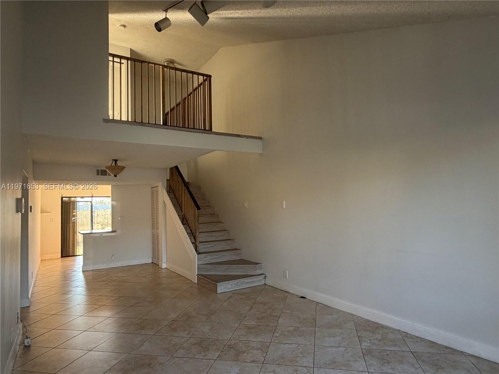 A living room features tile flooring, a staircase with a wooden railing, and a loft area — 3655 NW 111th Ter, Sunrise FL 33351, SUNRISE, FL
