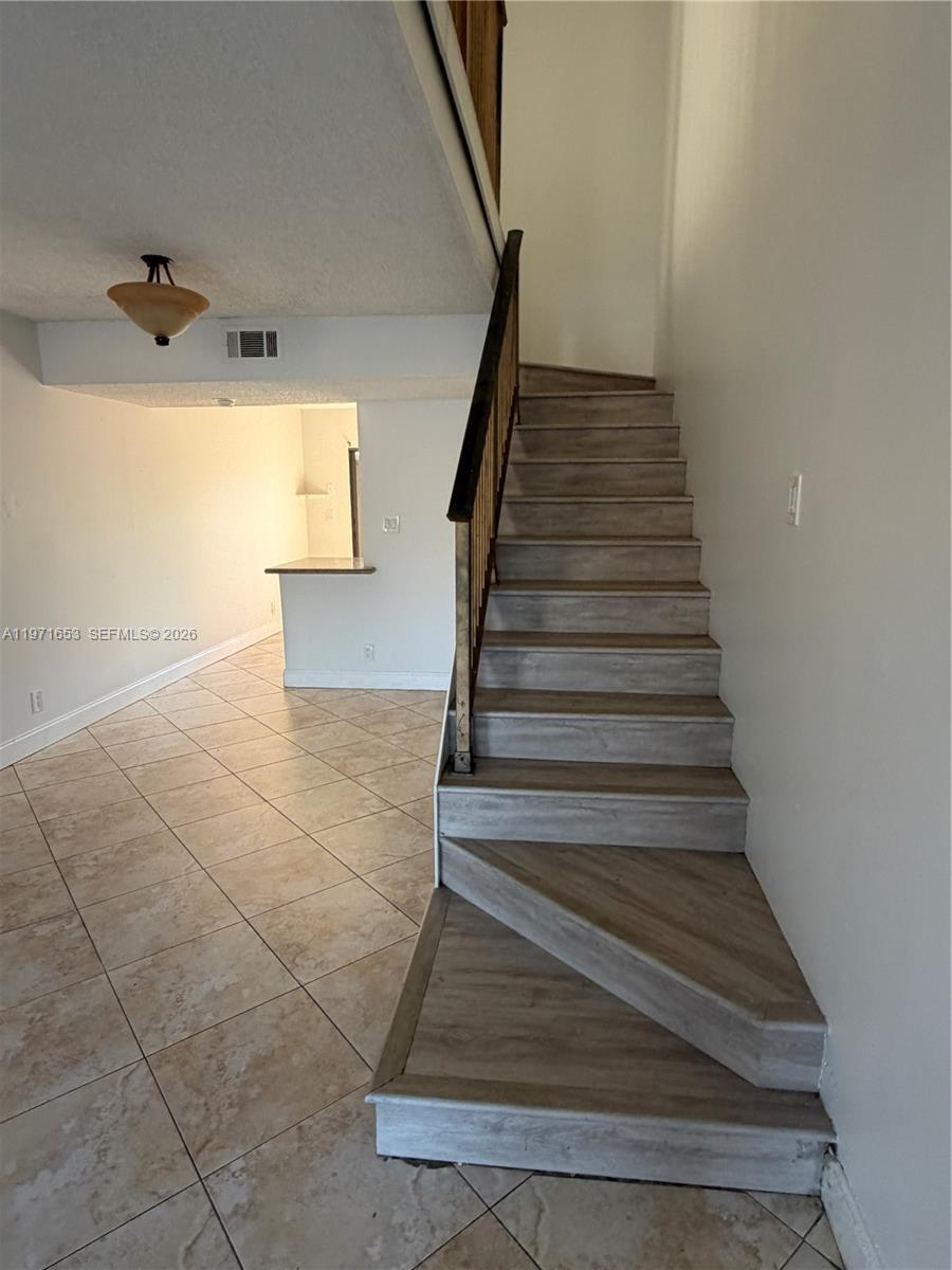 A staircase with wood-look treads leads upward next to a tiled living area — 3655 NW 111th Ter, Sunrise FL 33351, SUNRISE, FL