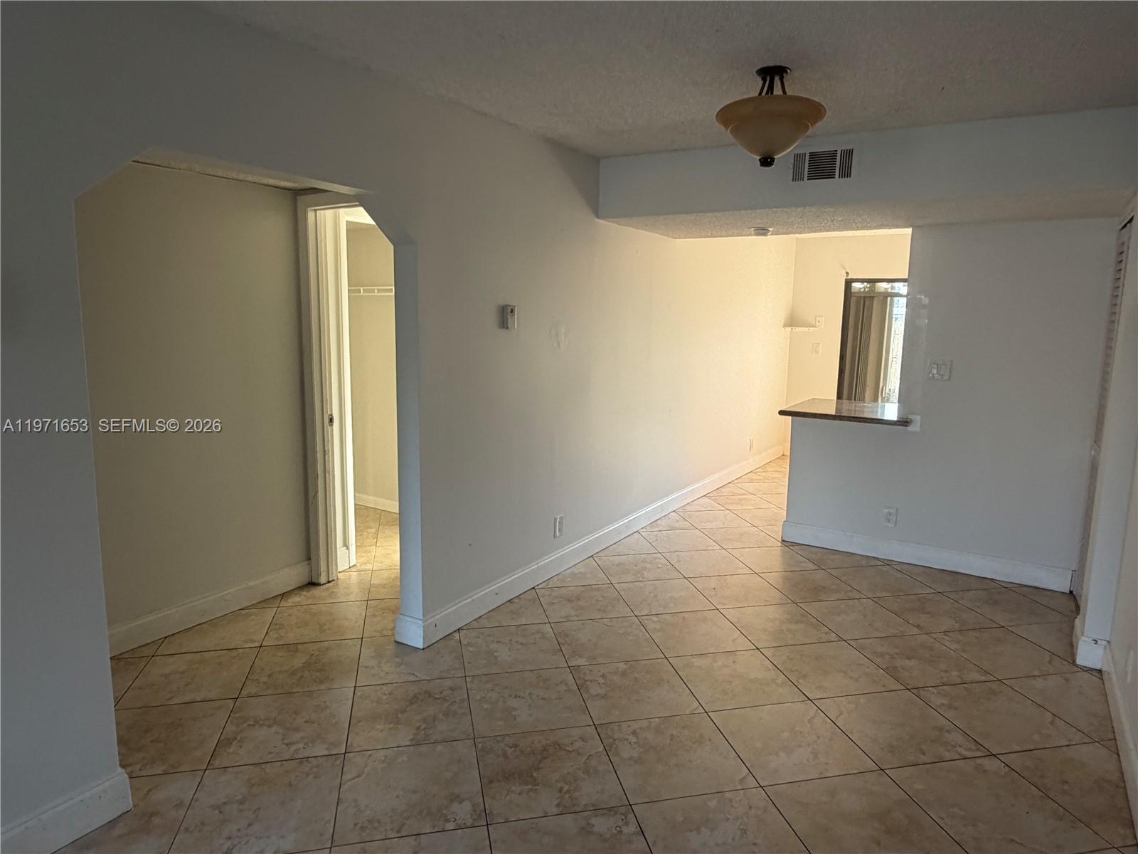 An interior view shows a tiled living area with an arched doorway and kitchen counter — 3655 NW 111th Ter, Sunrise FL 33351, SUNRISE, FL