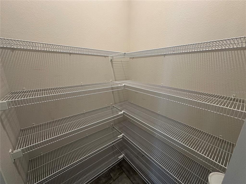 A walk-in pantry features white wire shelving installed along the corner walls — 5305 JUBILOSO DRIVE, ST CLOUD, FL