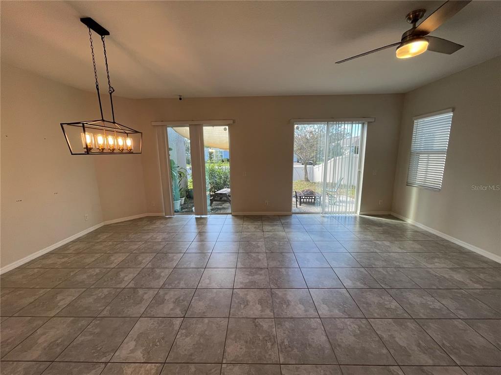 A spacious room with large floor tiles, a modern chandelier, and two sliding glass doors — 5305 JUBILOSO DRIVE, ST CLOUD, FL