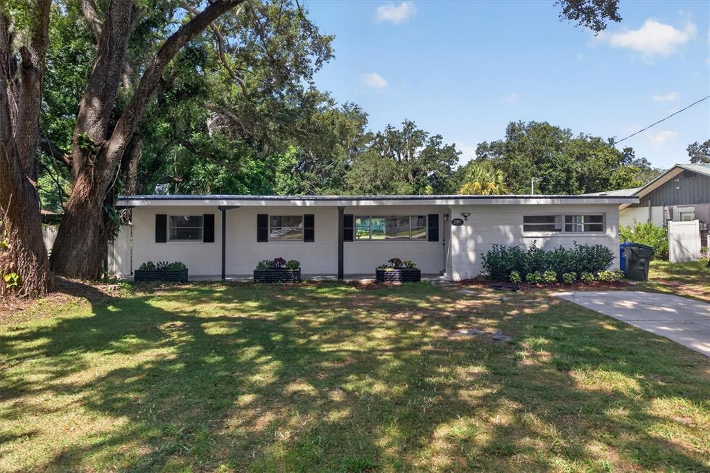 A single-story white brick house features a covered front porch and a large front yard — 2305 NEW JERSEY ROAD, LAKELAND, FL
