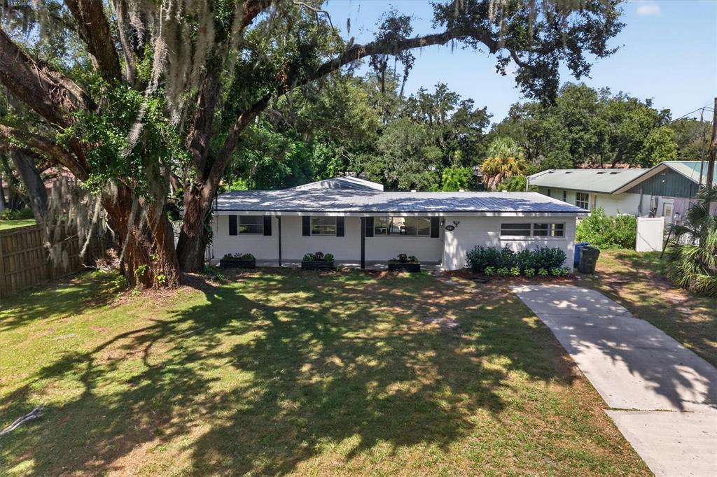 A single-story white house with a metal roof sits on a grassy lot with trees — 2305 NEW JERSEY ROAD, LAKELAND, FL
