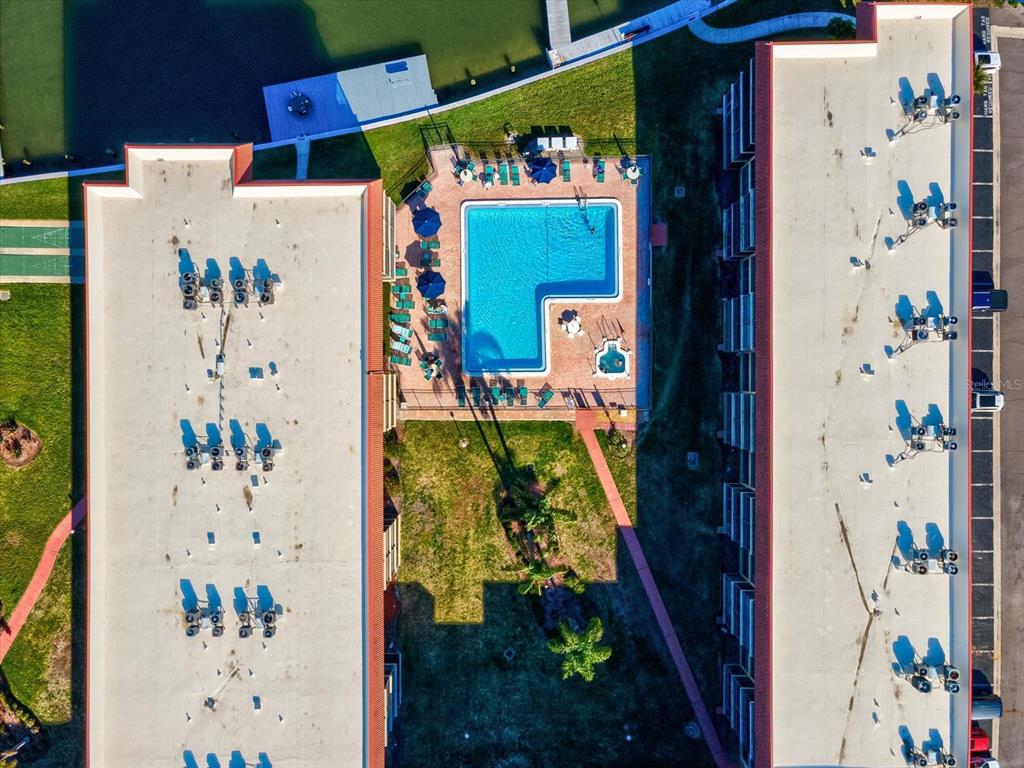 An aerial view shows two apartment buildings flanking a swimming pool and a grassy courtyard — 19701 GULF BOULEVARD UNIT 105, INDIAN SHORES, FL