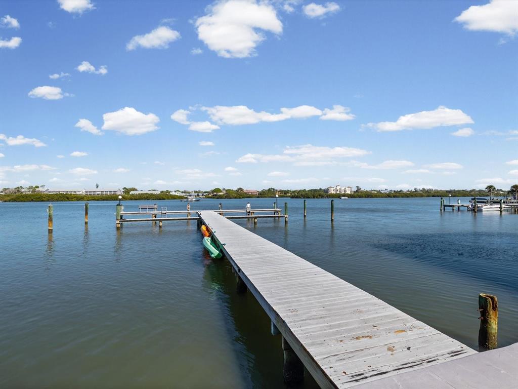 A long wooden dock extends into a calm bay under a bright blue sky — 19701 GULF BOULEVARD UNIT 105, INDIAN SHORES, FL