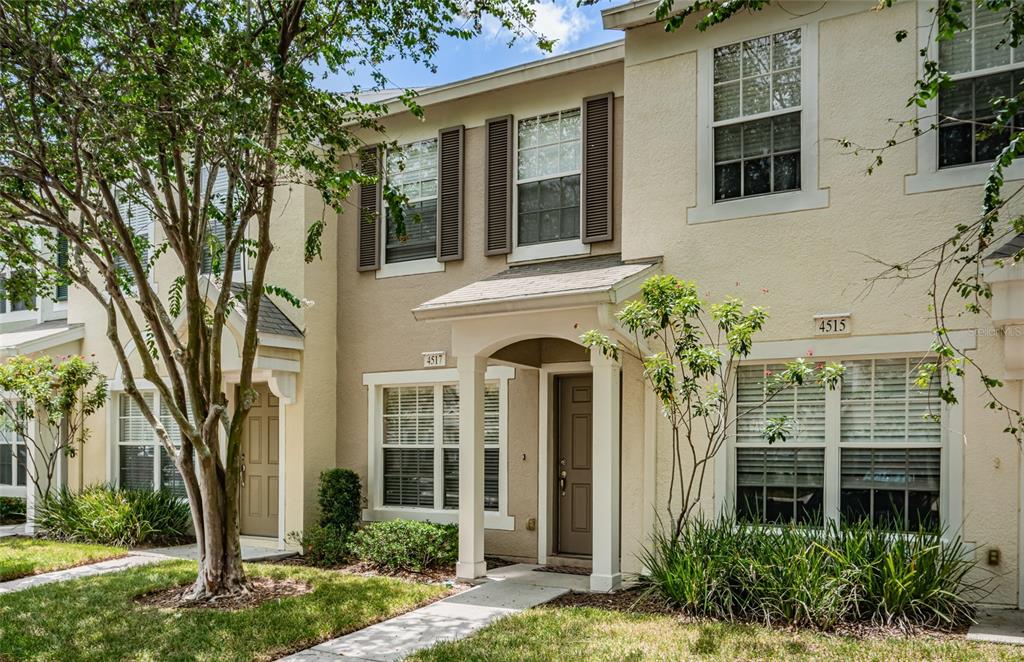The exterior of two adjacent townhomes features beige stucco walls, brown shutters, and covered entryways — 4517 KENNEWICK PLACE, RIVERVIEW, FL