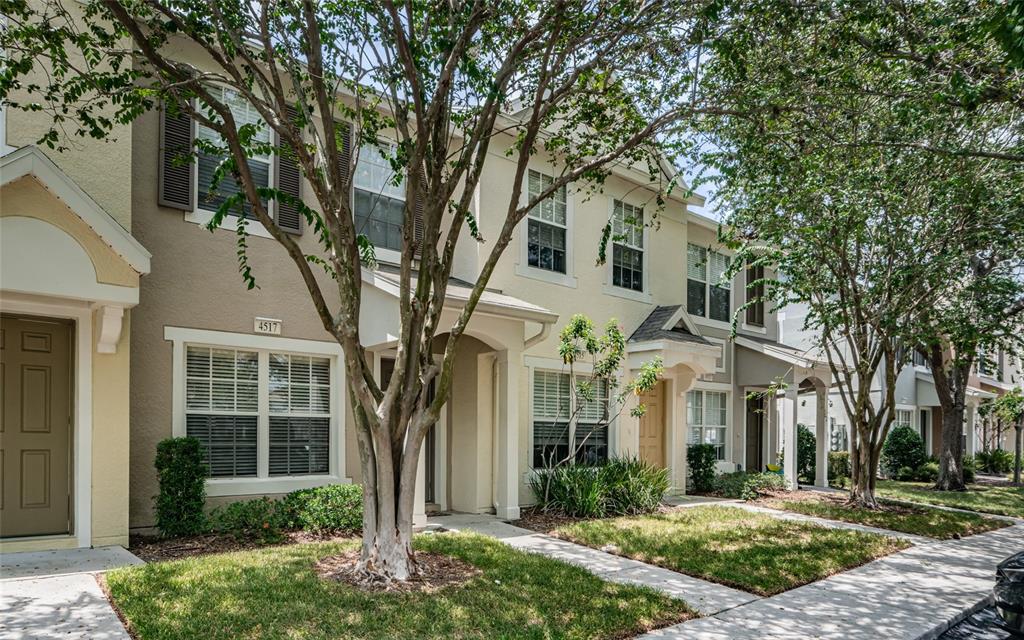 A row of two-story townhouses with beige stucco siding, brown shutters, and front entryways — 4517 KENNEWICK PLACE, RIVERVIEW, FL