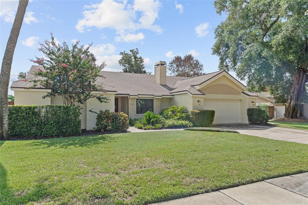A single-story house with a beige exterior, a chimney, and a two-car garage — 665 ROSEMERE CIRCLE, ORLANDO, FL