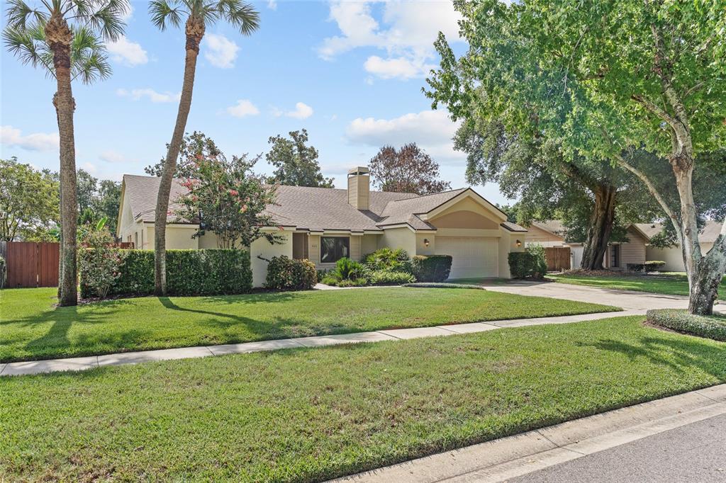 A single-story house with a tan exterior, a two-car garage, and palm trees in front — 665 ROSEMERE CIRCLE, ORLANDO, FL