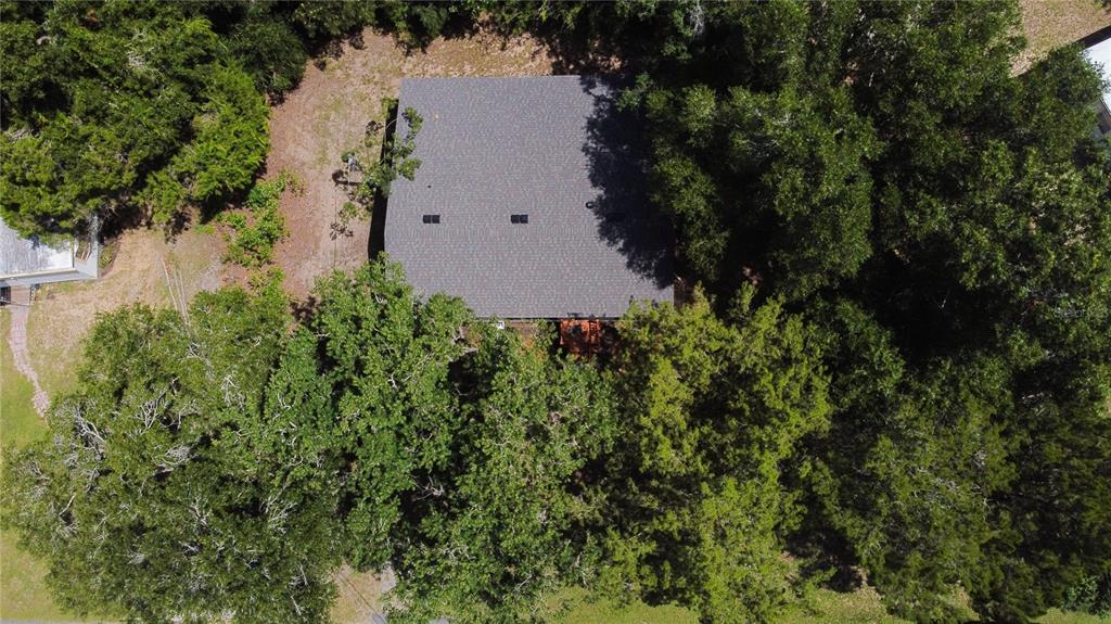 An aerial view shows a house with a dark shingled roof surrounded by dense trees — 8017 E SKYLINE LANE, FLORAL CITY, FL