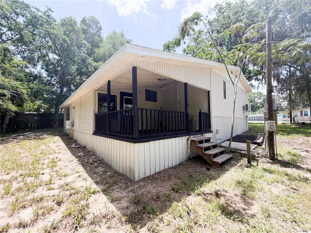 The exterior of a mobile home features a covered porch with black railings and stairs — 8017 E SKYLINE LANE, FLORAL CITY, FL