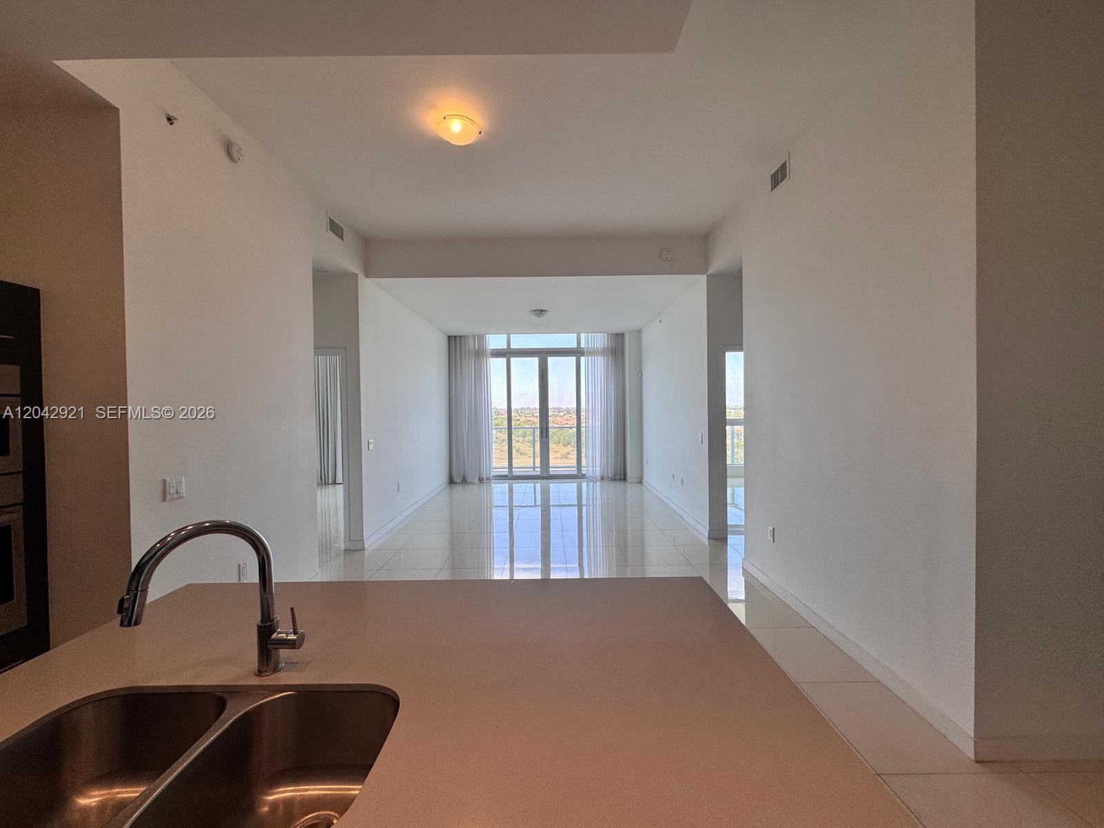 A view from a kitchen counter looking toward a living area with floor-to-ceiling windows — 7825 NW 107th Ave # 706, Doral FL 33178, DORAL, FL