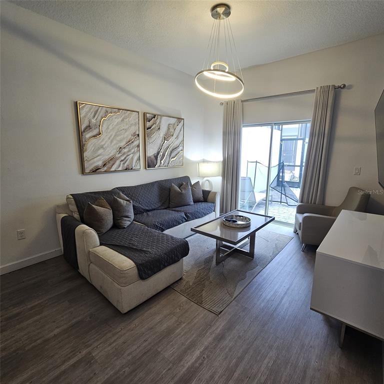 A living room features a sectional sofa, coffee table, area rug, and sliding glass doors — 379 FAMAGUSTA DRIVE, DAVENPORT, FL