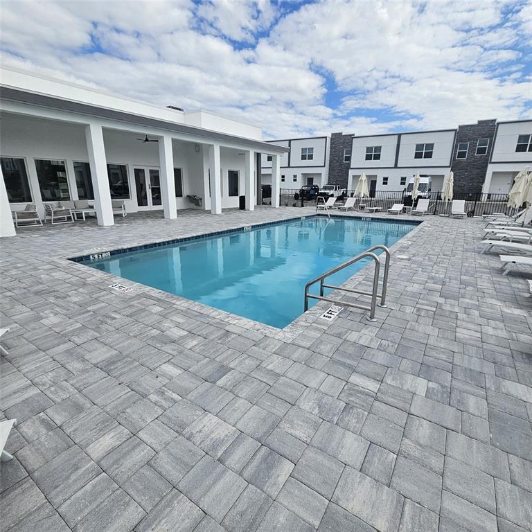 A rectangular swimming pool is surrounded by a gray paver deck and modern townhomes — 379 FAMAGUSTA DRIVE, DAVENPORT, FL