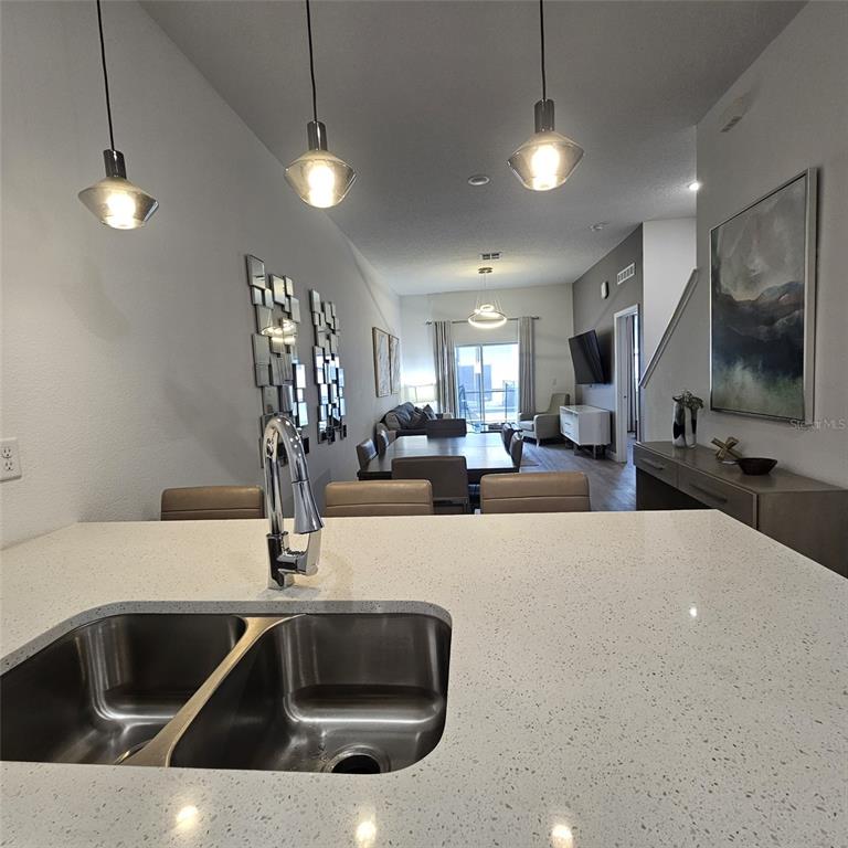 A kitchen island with a double sink overlooks an open-concept dining and living area — 379 FAMAGUSTA DRIVE, DAVENPORT, FL