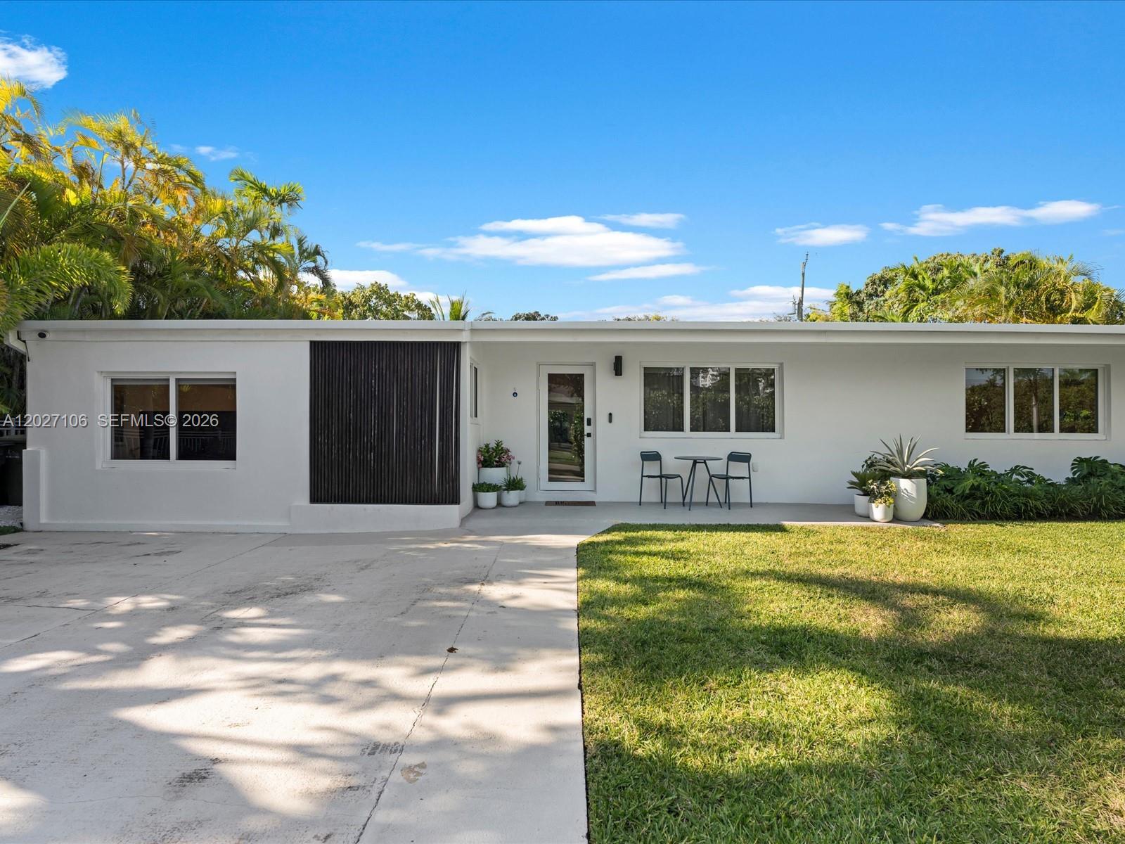 A single-story white house features a flat roof, a concrete driveway, and a front lawn — 1945 Alamanda Dr # 0, North Miami FL 33181, NORTH MIAMI, FL