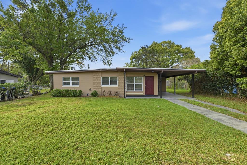 A single-story house with a tan exterior, a red front door, and an attached carport — 116 HOPE CIRCLE, ORLANDO, FL