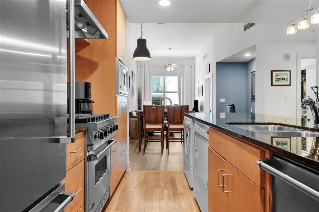 A galley kitchen with stainless steel appliances and wood cabinets opens into a dining area — 1120 E KENNEDY BOULEVARD UNIT 827, TAMPA, FL