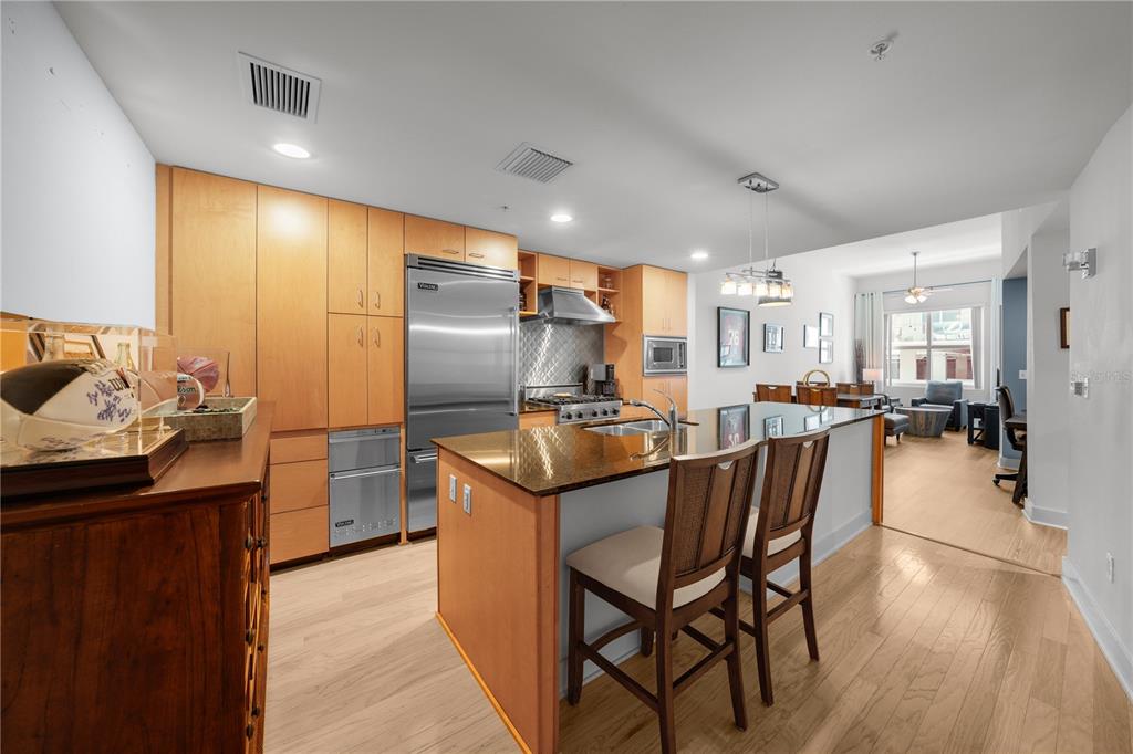 A modern kitchen features light wood cabinets, stainless steel appliances, and a granite-topped island — 1120 E KENNEDY BOULEVARD UNIT 827, TAMPA, FL