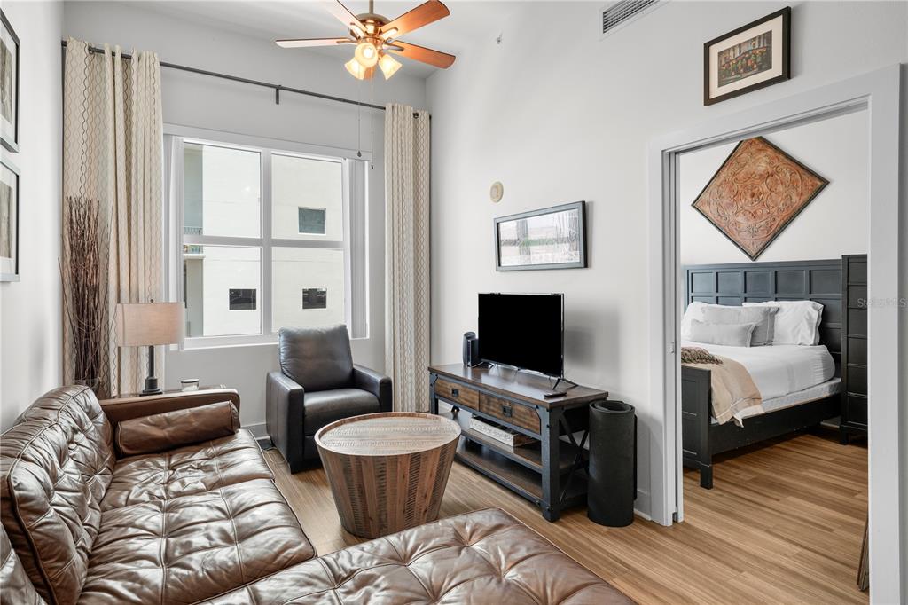 A living room with a leather sectional, wood coffee table, and an adjacent bedroom doorway — 1120 E KENNEDY BOULEVARD UNIT 827, TAMPA, FL