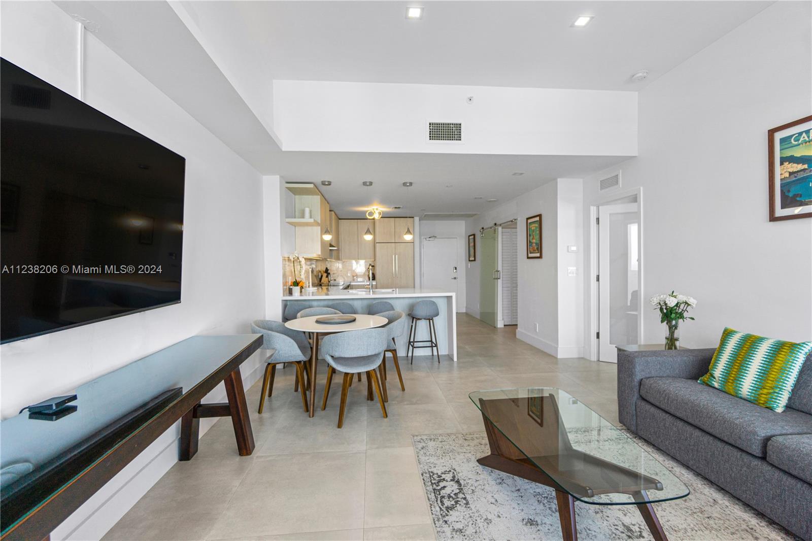 An open-concept living and dining area features light tile floors, a modern kitchen, and furniture — 100 Lincoln Rd # 1608, Miami Beach FL 33139, MIAMI BEACH, FL