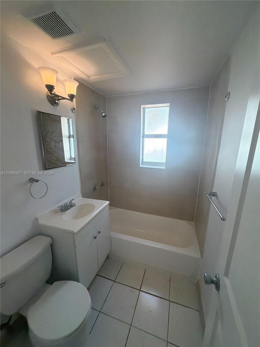 A bathroom features a white vanity, a toilet, and a shower-tub combo with tiled walls — 3669 Thomas Ave # 10, Miami FL 33133, MIAMI, FL