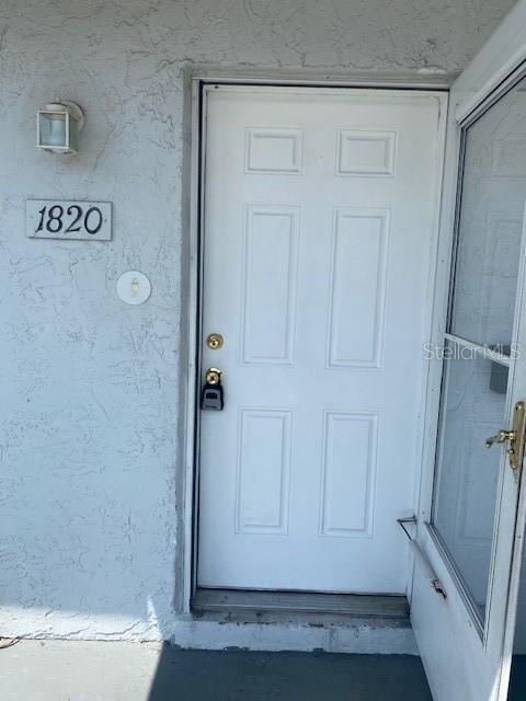 A white exterior door with a lockbox is mounted on a textured wall — 1820 Amberly Avenue # 10, Orlando FL 32822, ORLANDO, FL