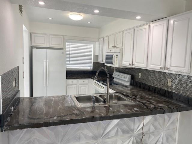 A kitchen features white cabinets, dark marble-look countertops, a double sink, and a white refrigerator — 1820 Amberly Avenue # 10, Orlando FL 32822, ORLANDO, FL