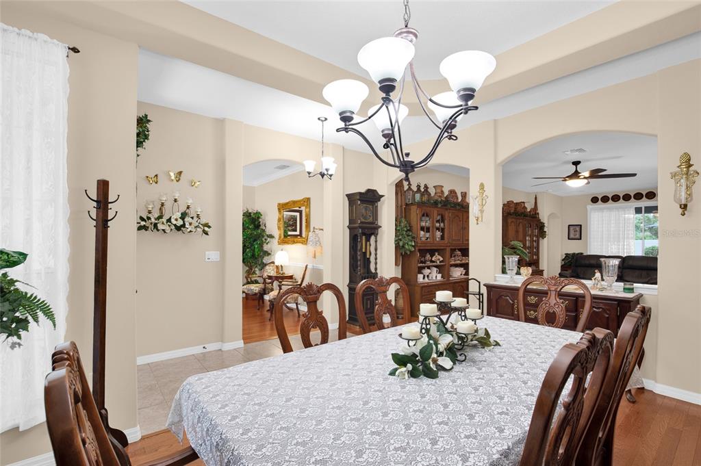 A formal dining room features a large table, a chandelier, and an adjacent living area — 16411 SW 14TH AVENUE ROAD, OCALA, FL