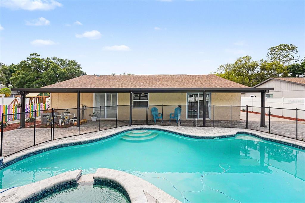 A backyard features a swimming pool, a hot tub, and a covered patio area — 12601 WOOD IBIS WAY, TAMPA, FL