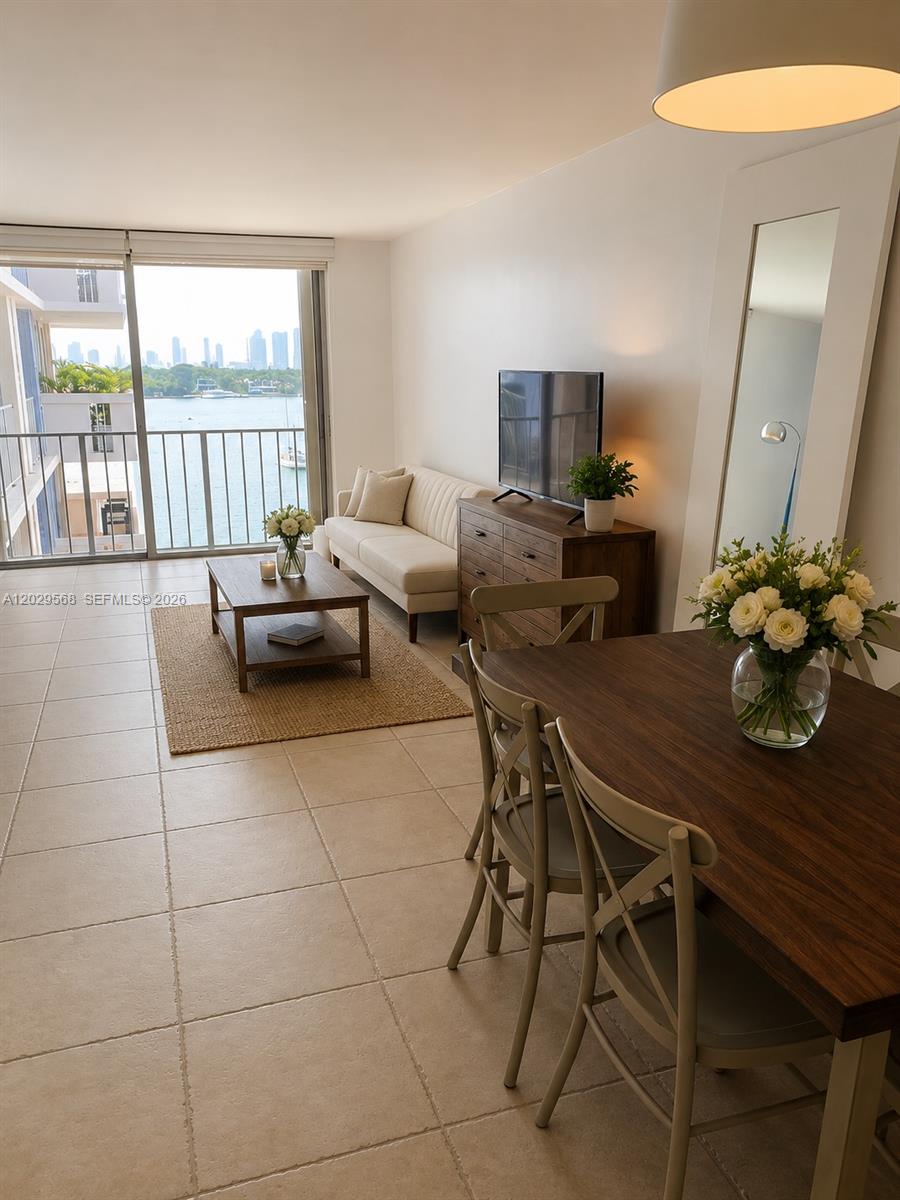 A living and dining area features tile floors, a balcony with water views, and furniture — 800 West Ave # 715, Miami Beach FL 33139, MIAMI BEACH, FL