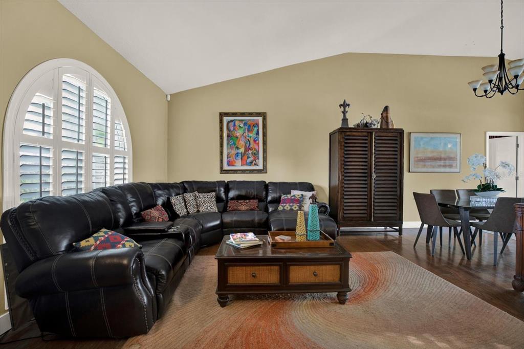 A living room features a large black leather sectional, a wooden coffee table, and arched windows — 804 SANDY TRAIL PLACE, BRANDON, FL