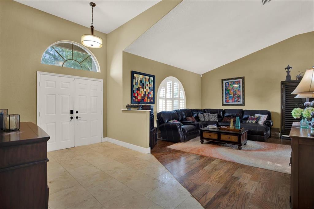 A living room with tile and wood flooring, a black leather sectional, and arched windows — 804 SANDY TRAIL PLACE, BRANDON, FL