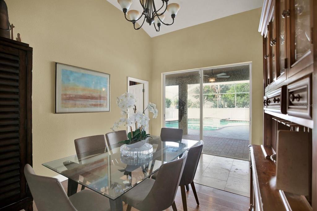 A dining room with a glass table, six chairs, and sliding doors leading to a pool — 804 SANDY TRAIL PLACE, BRANDON, FL