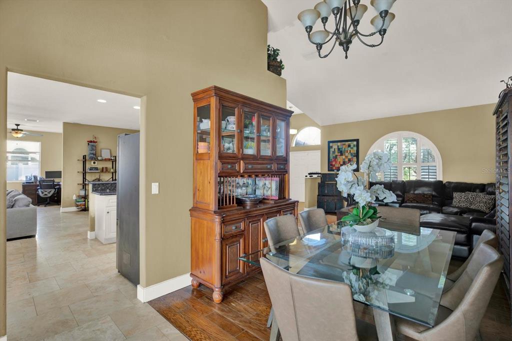 A dining area with a glass table and hutch opens into a kitchen and living room — 804 SANDY TRAIL PLACE, BRANDON, FL