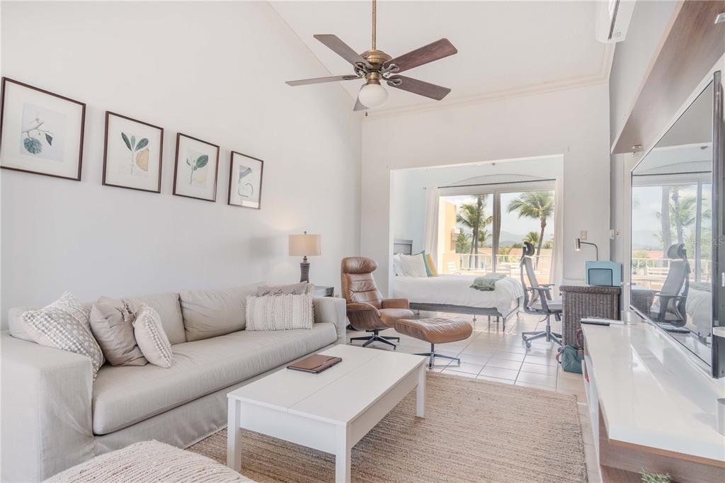 A living room with a sofa, coffee table, and an adjacent bedroom with a view — 150 CANDELERO DRIVE DRIVE UNIT 878-studio, HUMACAO, PR