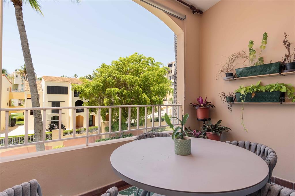 A balcony features a round table, chairs, wall-mounted planters, and a view of nearby buildings — 150 CANDELERO DRIVE DRIVE UNIT 878-studio, HUMACAO, PR