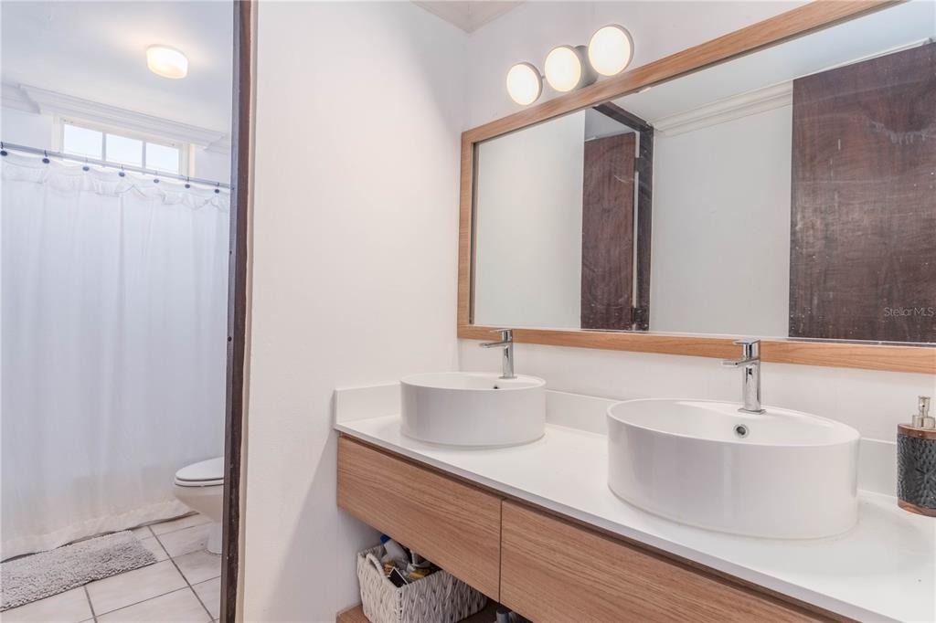 A bathroom features a double vanity with vessel sinks, wood cabinetry, and a large mirror — 150 CANDELERO DRIVE DRIVE UNIT 878-studio, HUMACAO, PR