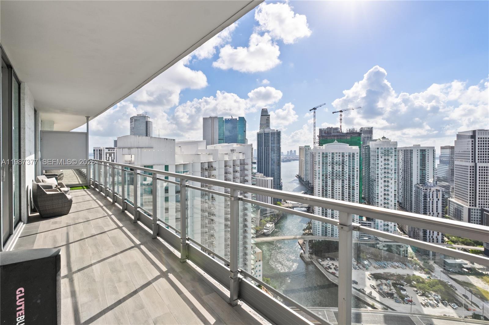 A high-rise balcony with glass railings overlooks a city skyline and a river — 90 SW 3rd St # 4301, Miami FL 33130, MIAMI, FL