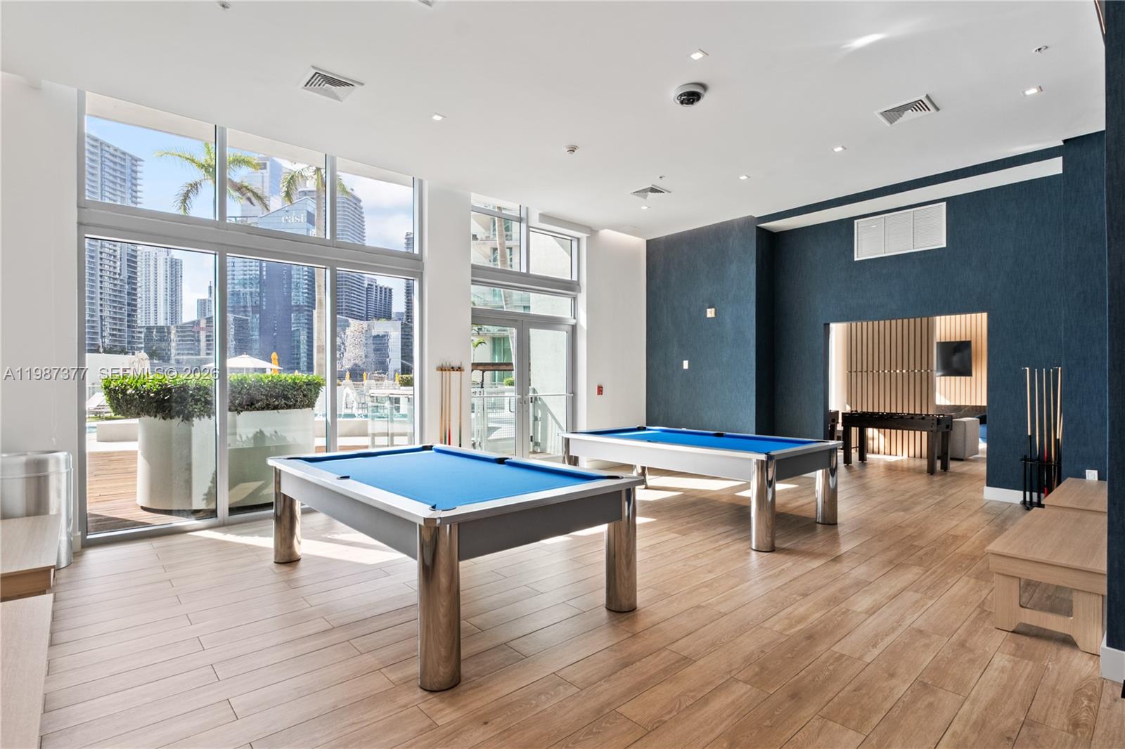 A game room features two blue pool tables, wood-look flooring, and floor-to-ceiling windows — 90 SW 3rd St # 4301, Miami FL 33130, MIAMI, FL
