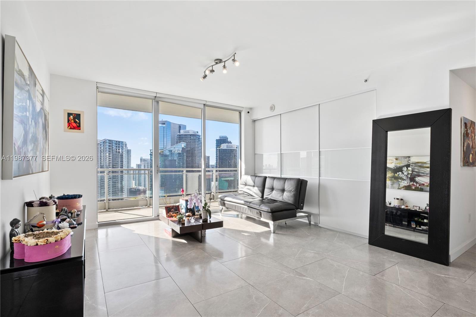 A modern living room features tile floors, a black sofa, and floor-to-ceiling windows with city views — 90 SW 3rd St # 4301, Miami FL 33130, MIAMI, FL