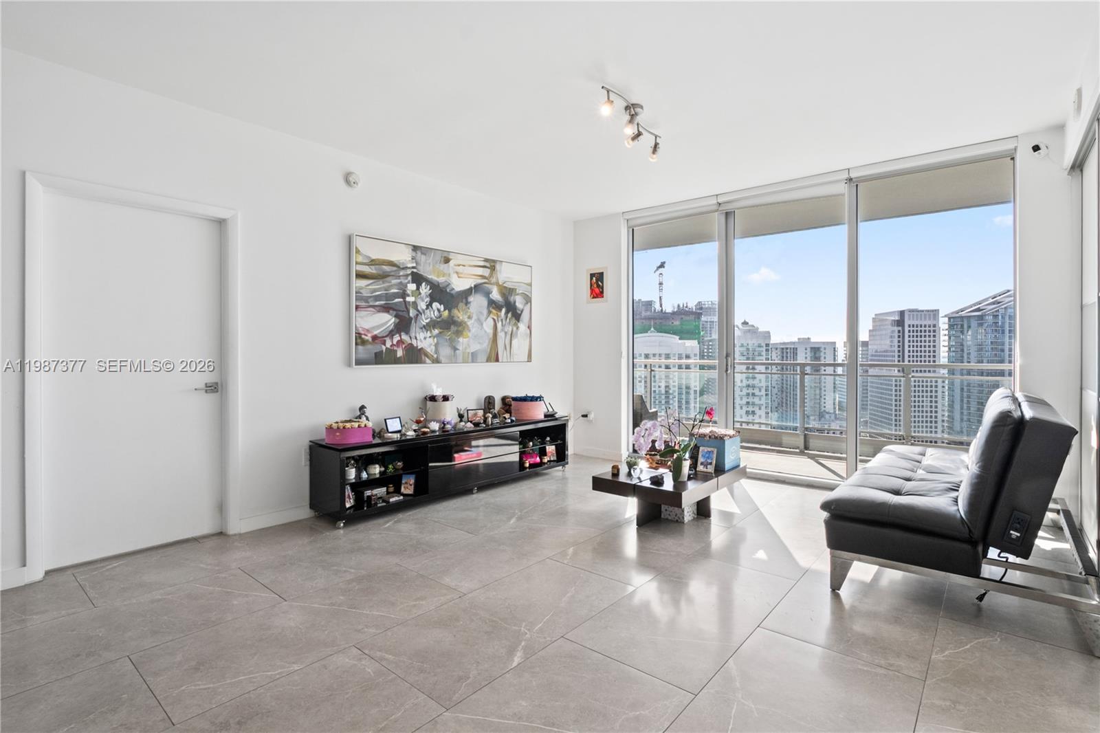 A modern living room features large gray floor tiles, a black console, and floor-to-ceiling windows — 90 SW 3rd St # 4301, Miami FL 33130, MIAMI, FL