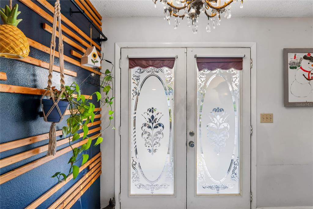 An entryway features double glass-paneled doors, a blue accent wall with wooden slats, and a chandelier — 13100 WESTERN CIRCLE, HUDSON, FL