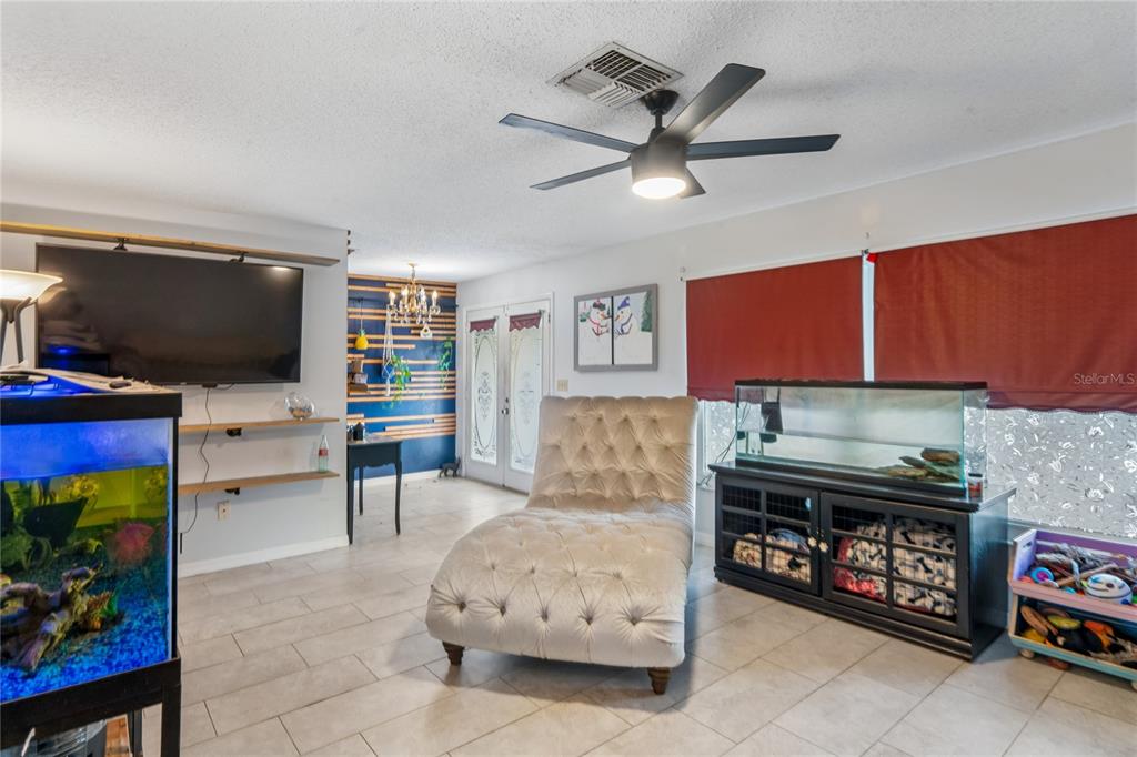 A living room features a tufted chaise lounge, two fish tanks, and a ceiling fan — 13100 WESTERN CIRCLE, HUDSON, FL