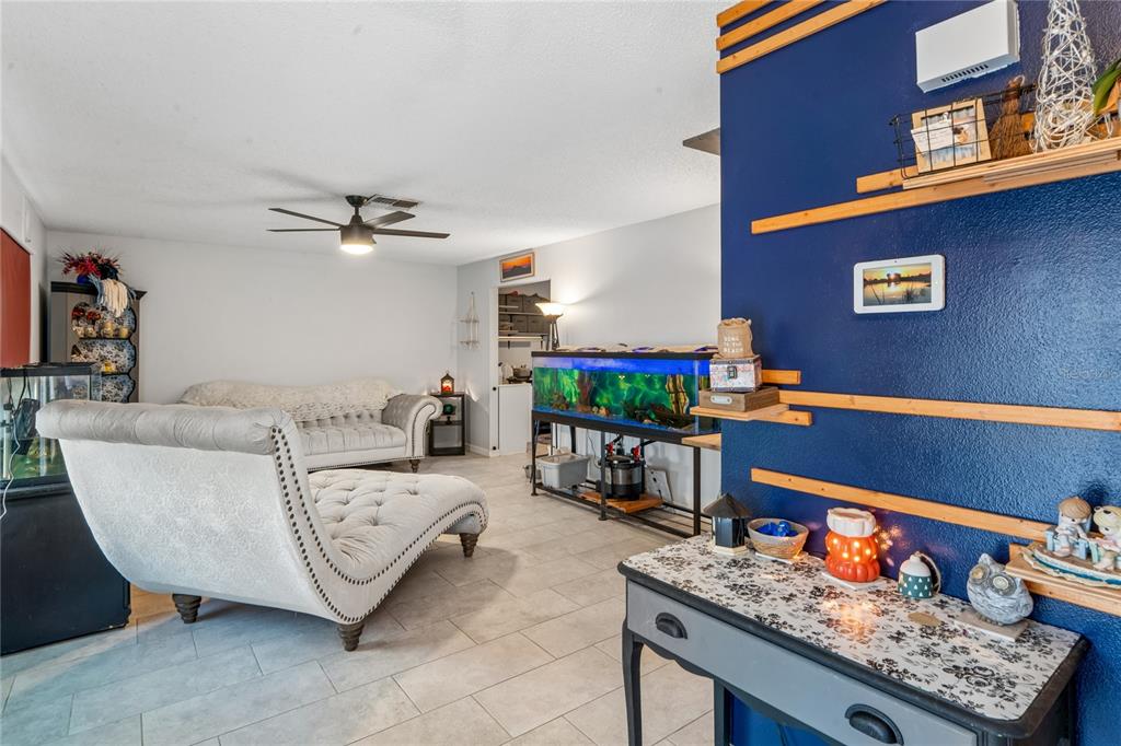 A living room features a tufted chaise lounge, a large fish tank, and a blue wall — 13100 WESTERN CIRCLE, HUDSON, FL