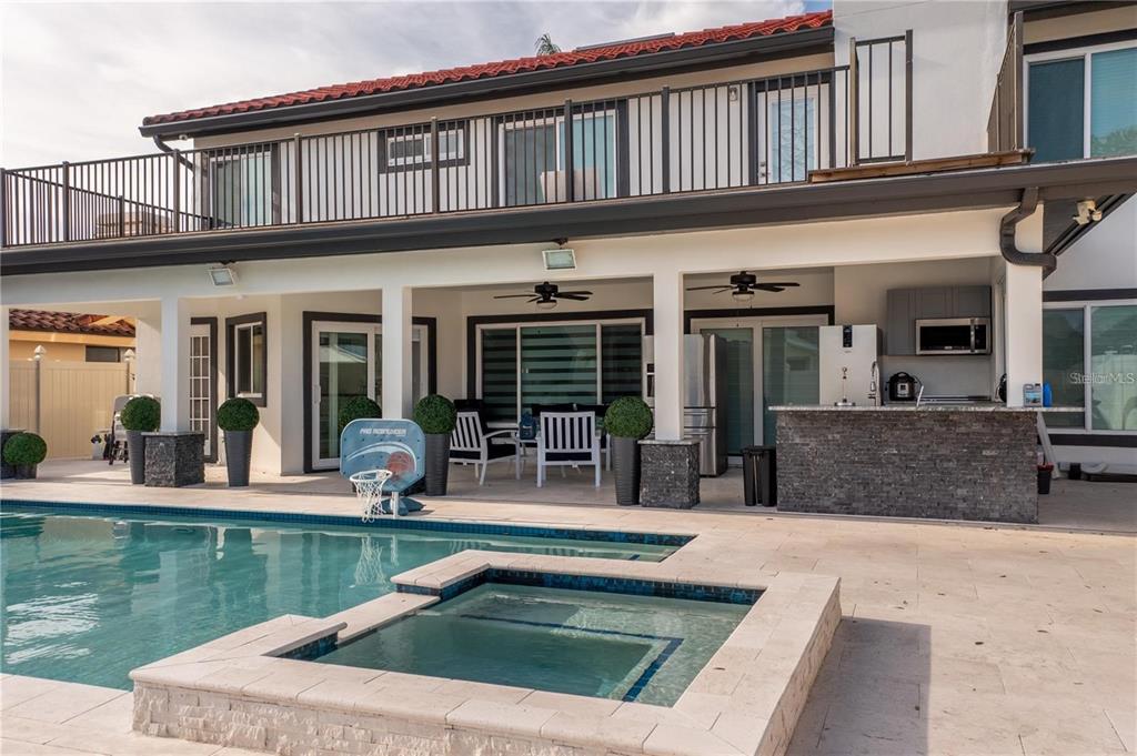 A backyard patio features a swimming pool, hot tub, outdoor kitchen, and a second-story balcony — 4123 CROSSWATER DRIVE, TAMPA, FL