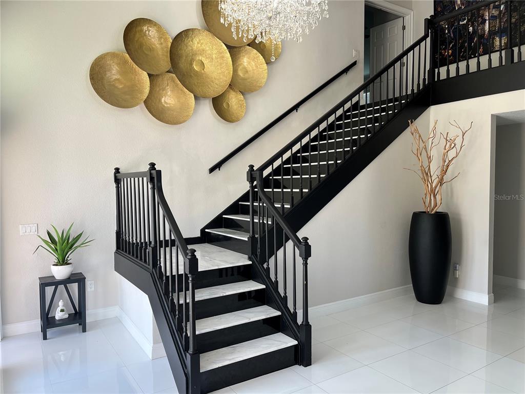 A staircase with black railings and white marble steps stands in a bright entryway — 4123 CROSSWATER DRIVE, TAMPA, FL