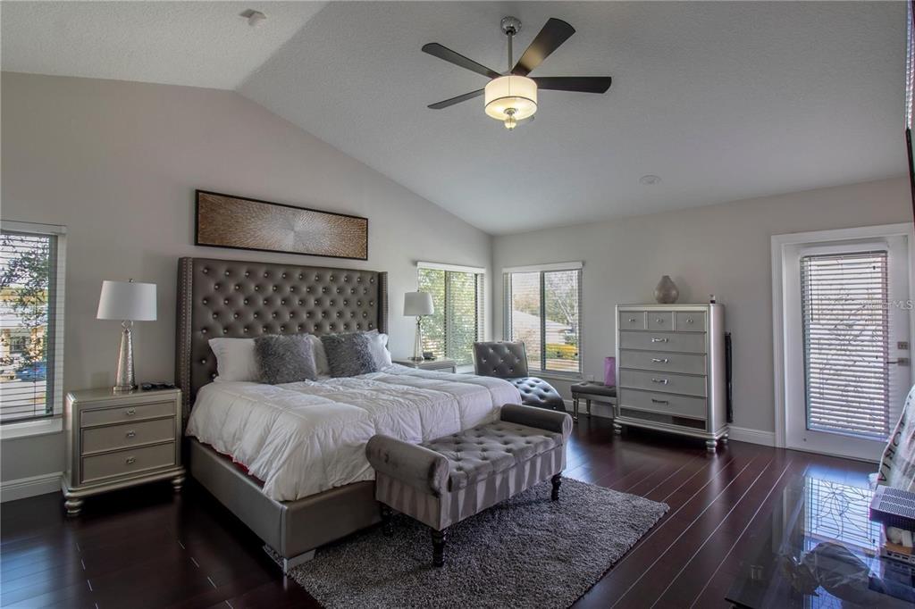 A bedroom features a tufted headboard, dark wood floors, a ceiling fan, and a dresser — 4123 CROSSWATER DRIVE, TAMPA, FL