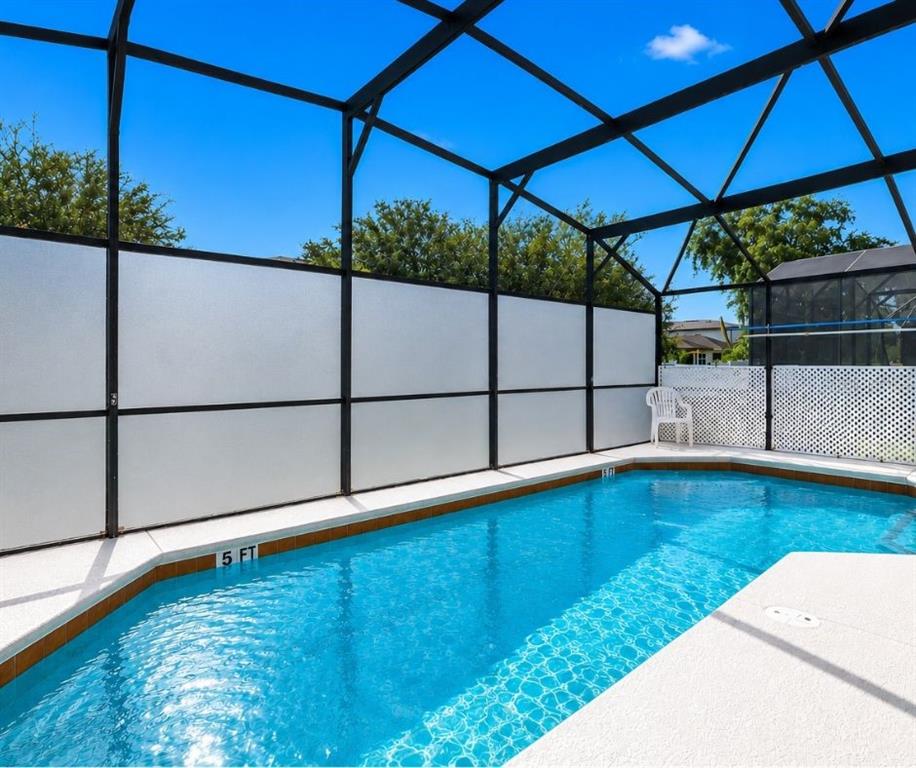 A swimming pool is enclosed by a black metal screen structure with frosted privacy panels — 1255 SEASONS BOULEVARD, KISSIMMEE, FL